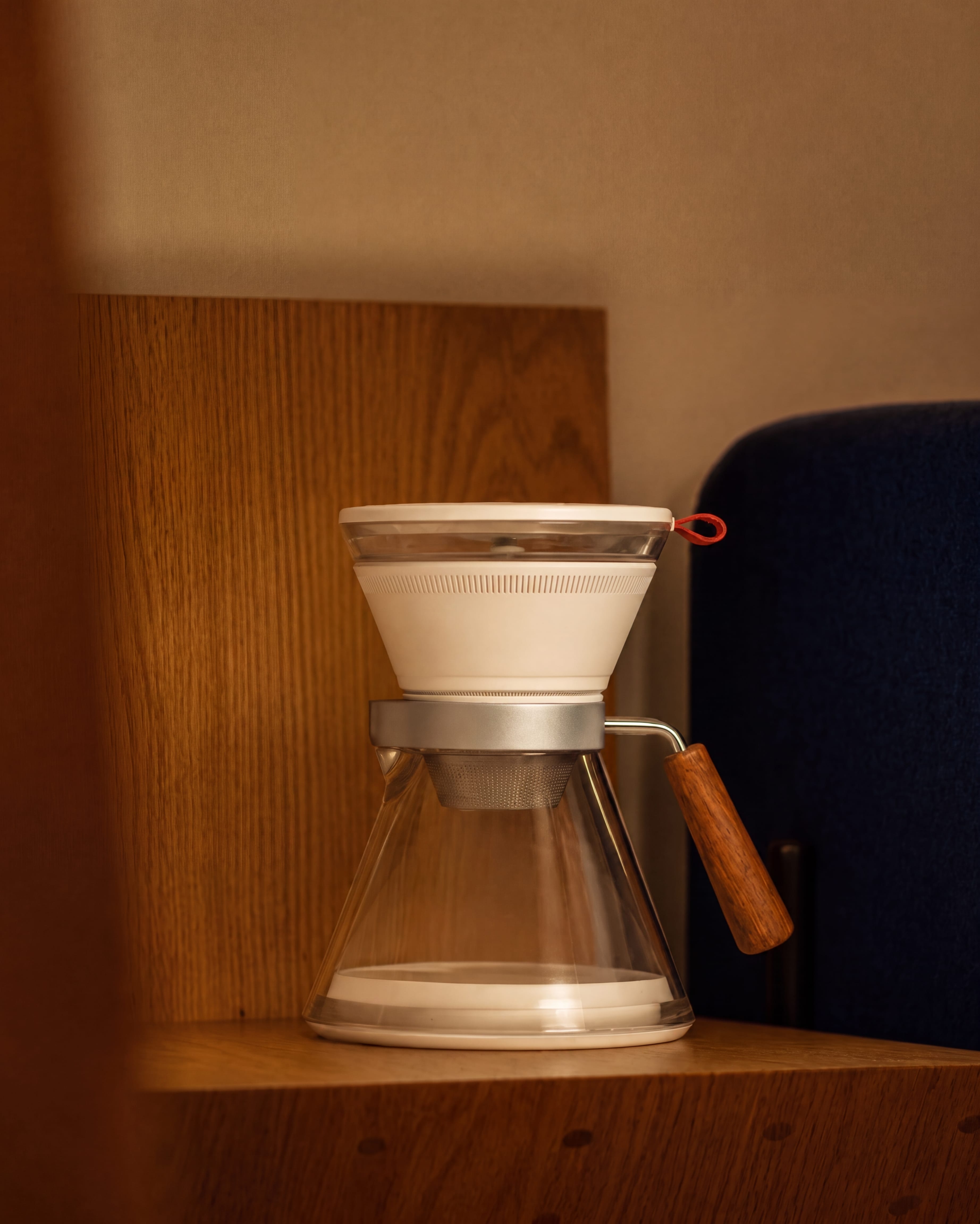 CoolDrip placed on a warm wooden shelf beside a dark blue chair