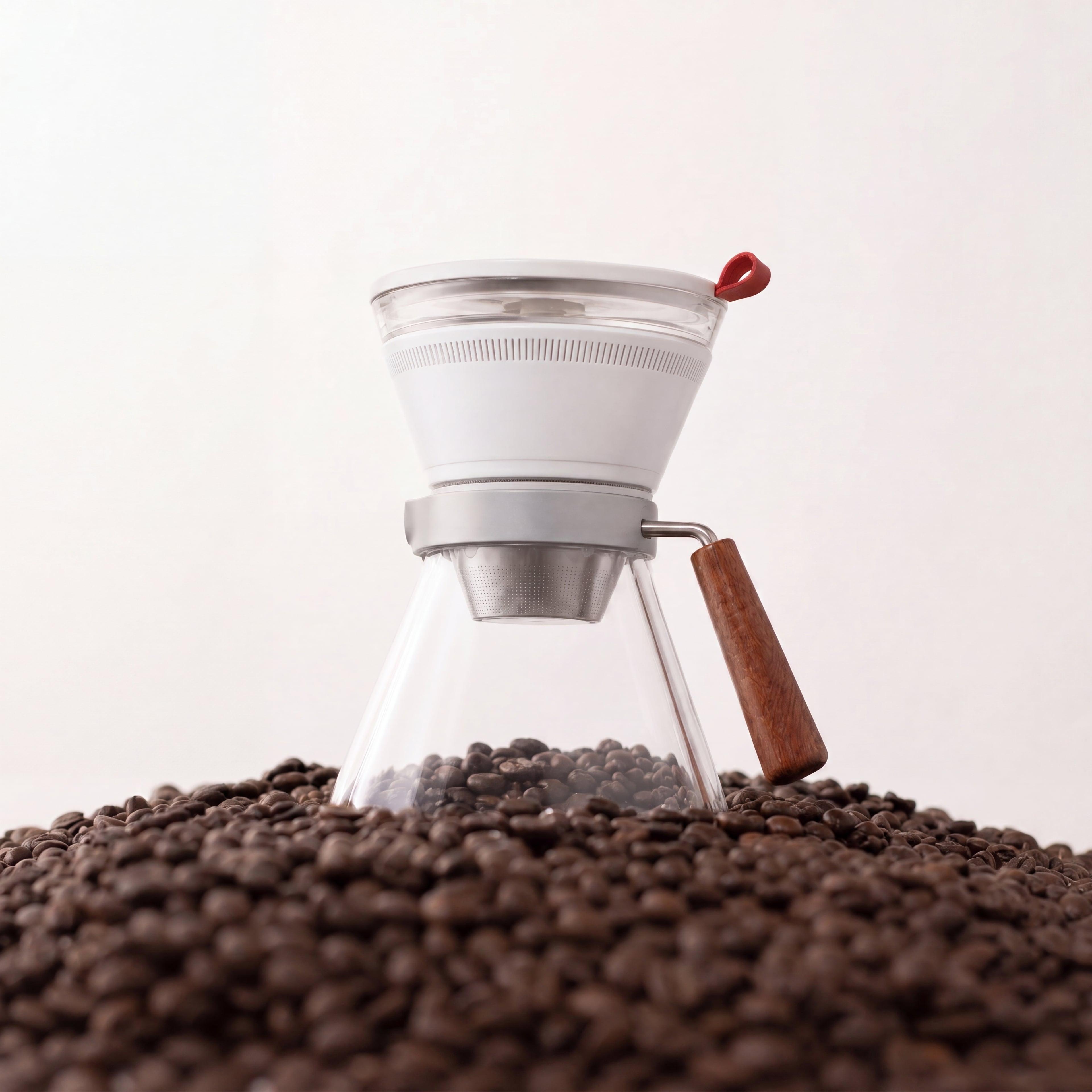CoolDrip with a white brew body, glass carafe, and wood handle resting on coffee beans